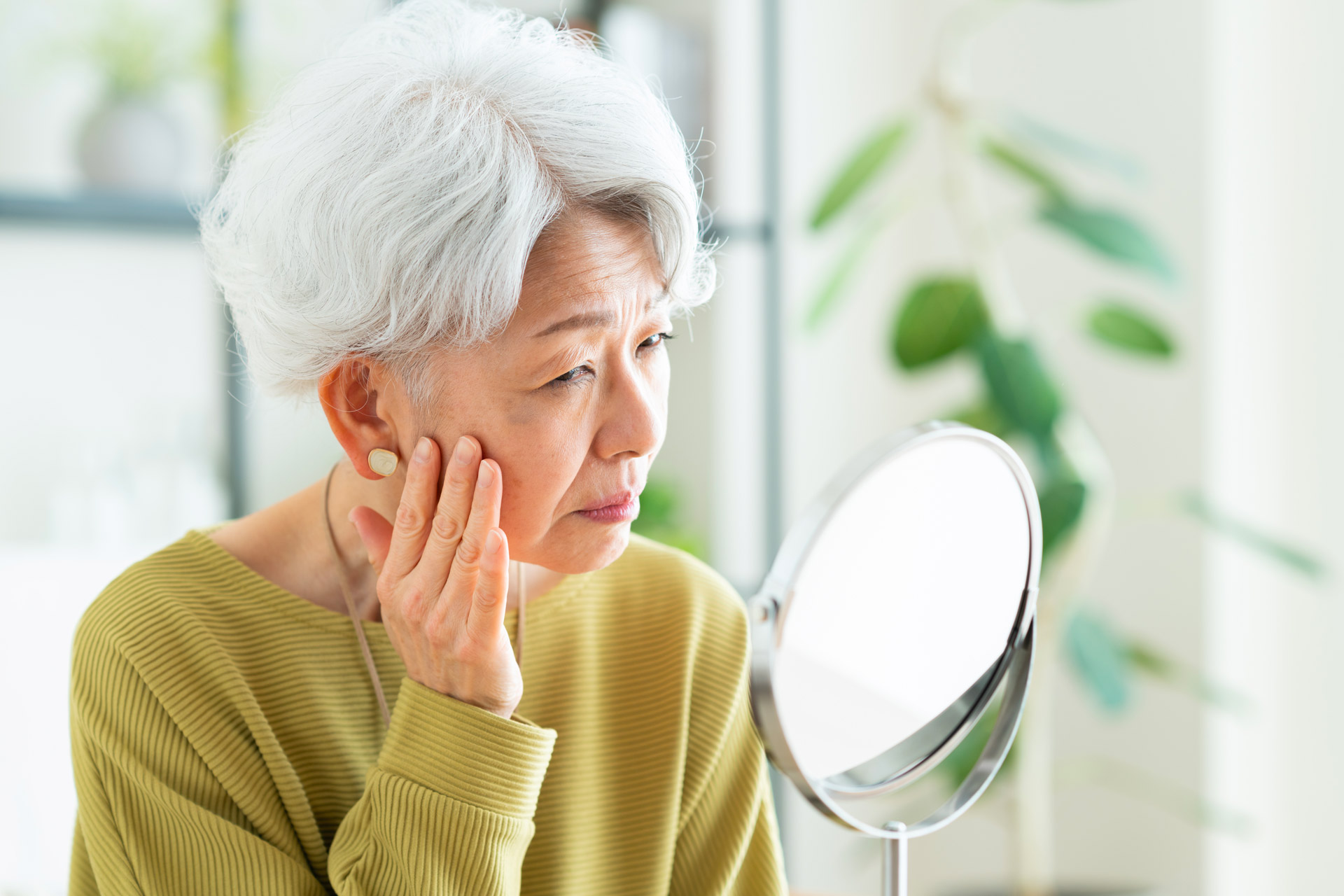 Femme qui regarde çà peau dans un mirroir